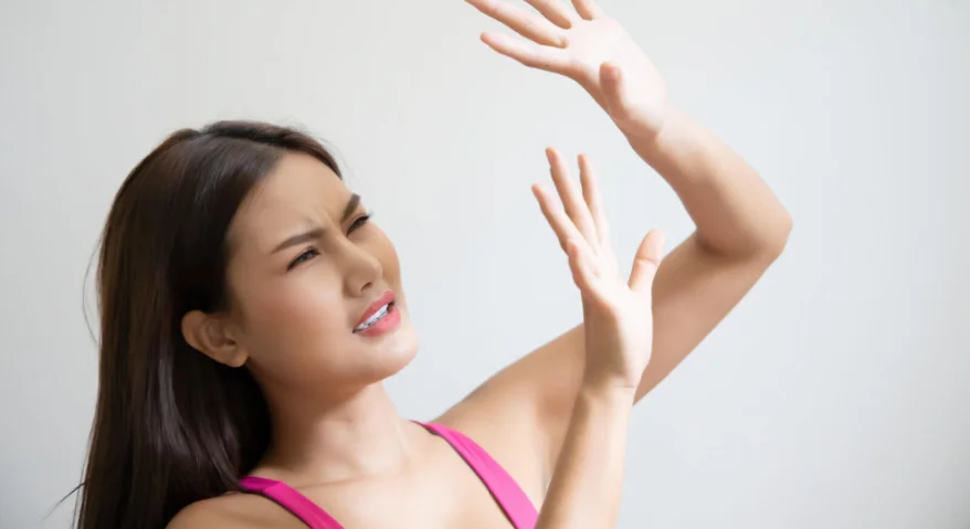 A young woman frowned, raising her hand to shield her face from the intense, blinding sunlight.