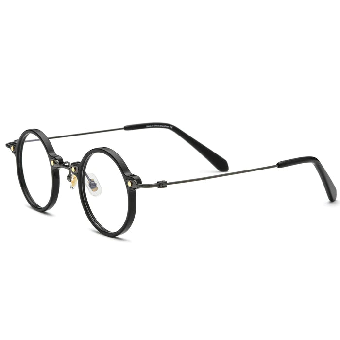 A side view of black, round, metal-framed glasses, featuring slender temples and gold metal rivet details at the bridge.