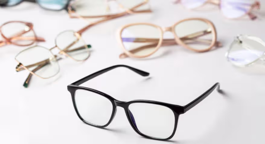 Black rectangular eyeglasses displayed with various eyewear frames in the background
