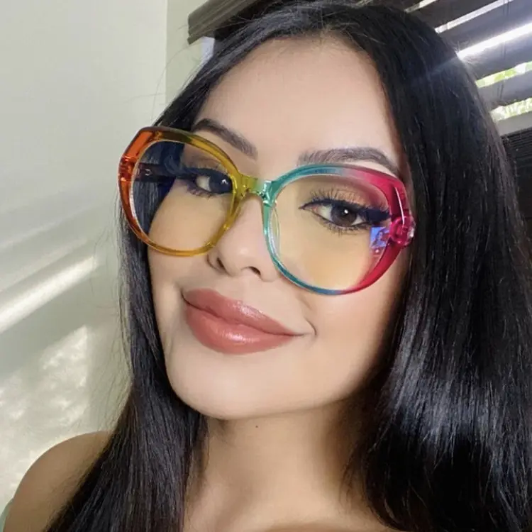 A long-haired woman is wearing a pair of large, round glasses featuring a vibrant rainbow gradient frame that transitions through shades of red, yellow, green, and blue.