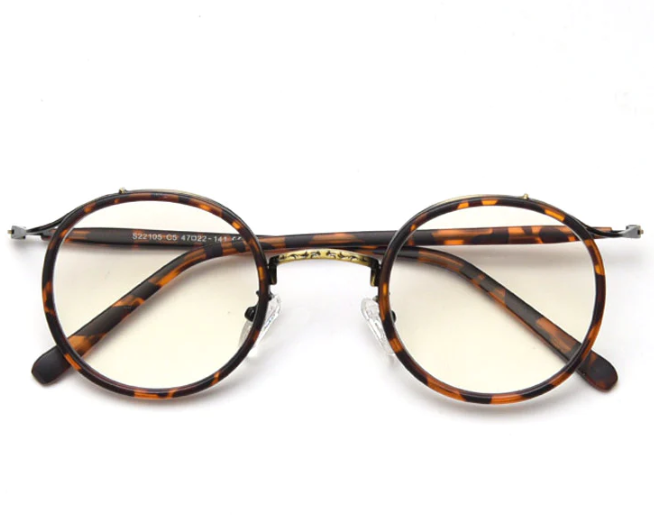 A front view of classic, thin-rimmed, round tortoiseshell glasses, featuring vintage-style engraved metal detailing on the bridge.