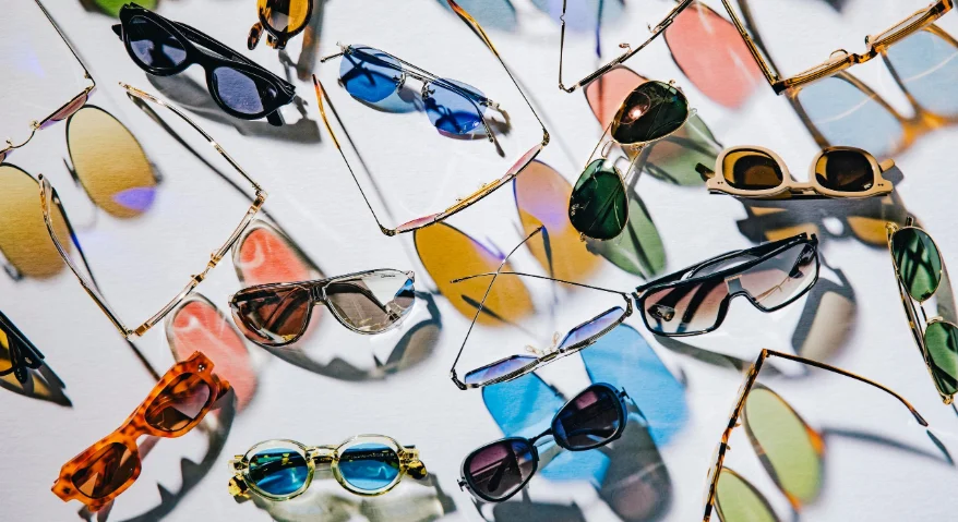 Polarized sunglasses of various styles and colors lay scattered haphazardly across the table.