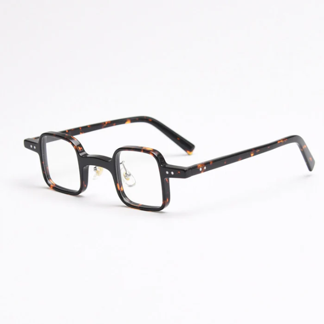 A side view of small, square, tortoiseshell-patterned glasses, featuring a strong vintage aesthetic and equipped with metal nose pads.