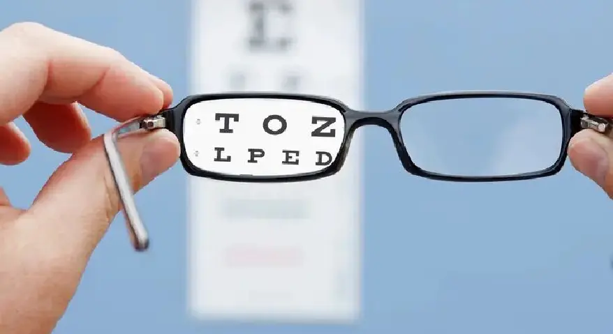 Viewing an eye chart through a pair of prescription glasses, the letters within the lenses appear sharp while the background remains blurred, demonstrating the effect of vision correction.