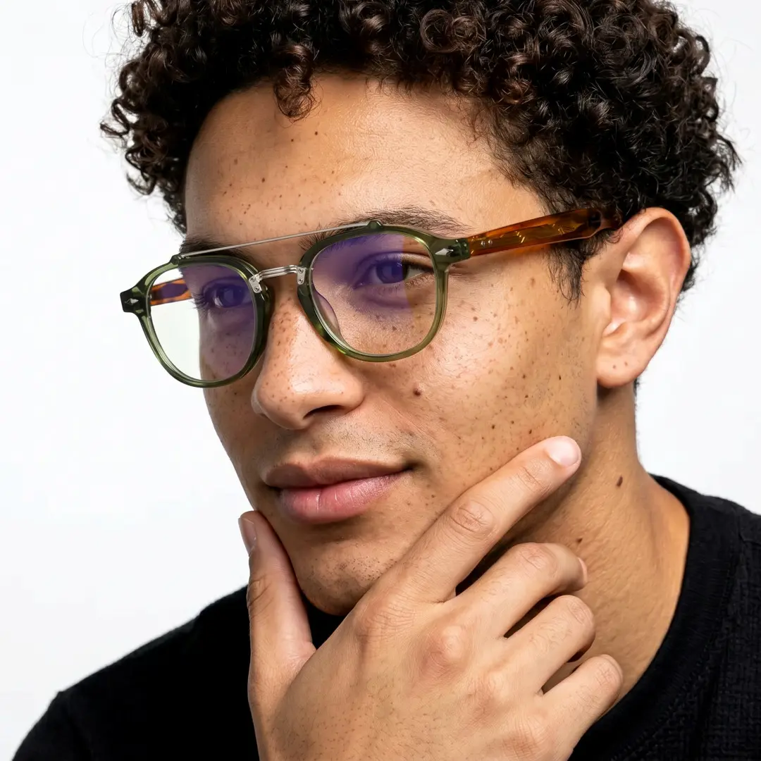 Three-quarter view of male wearing vintage green aviator eyeglasses, hand resting on chin, neutral expression, AA0142603