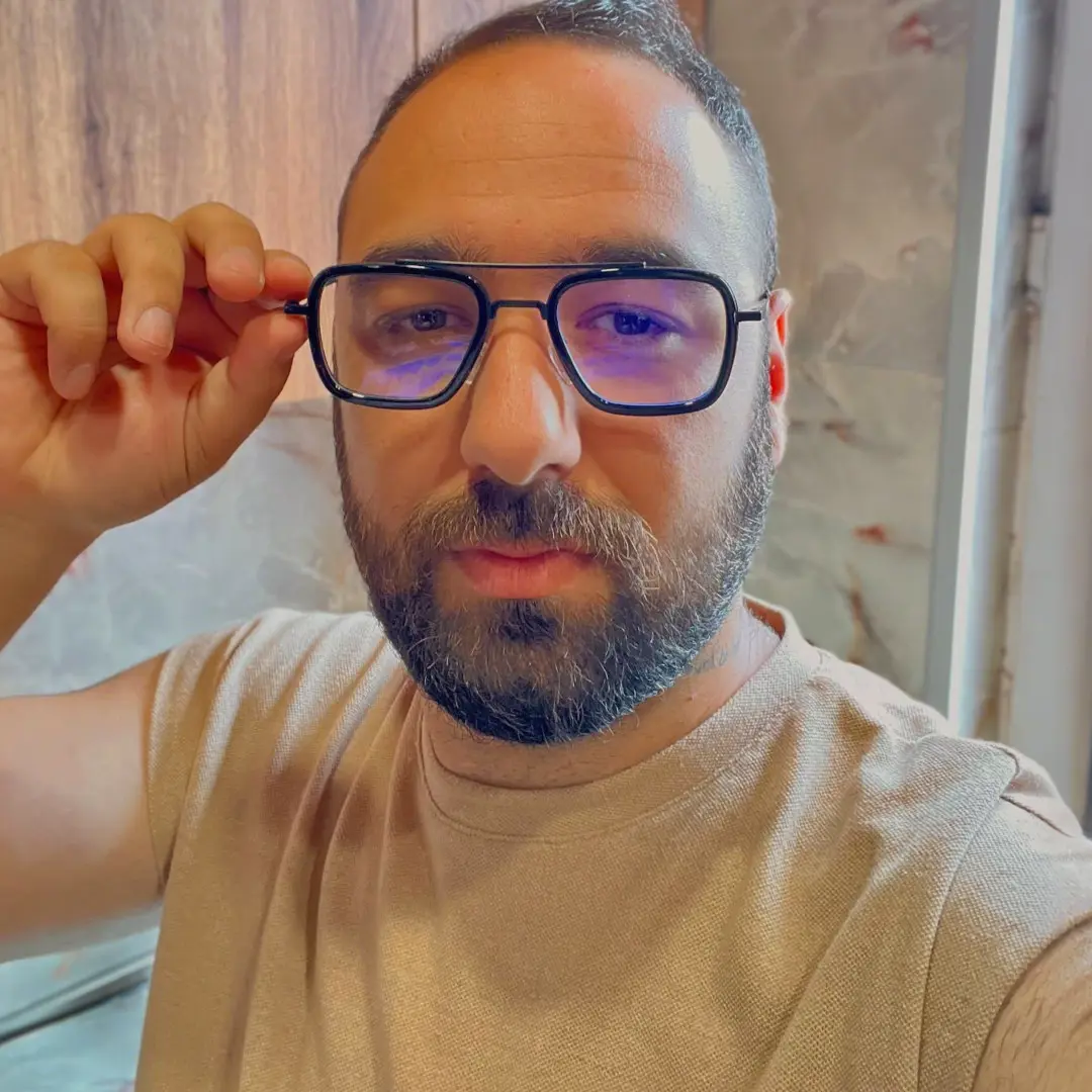 Front view of male wearing black aviator eyeglasses, adjusting glasses, neutral expression, AM0192409