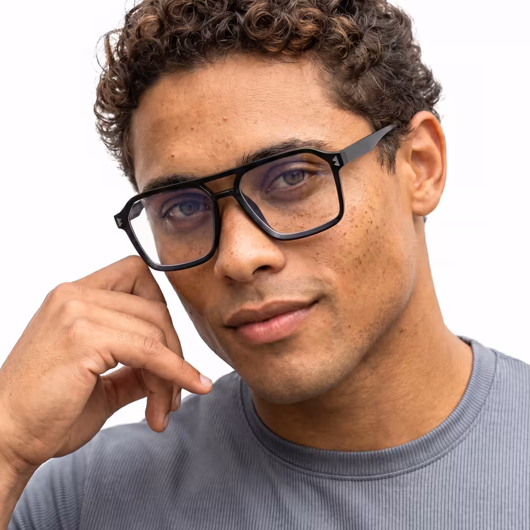 Three-quarter view of male wearing black aviator eyeglasses, hand near face, soft smile, AR0042605