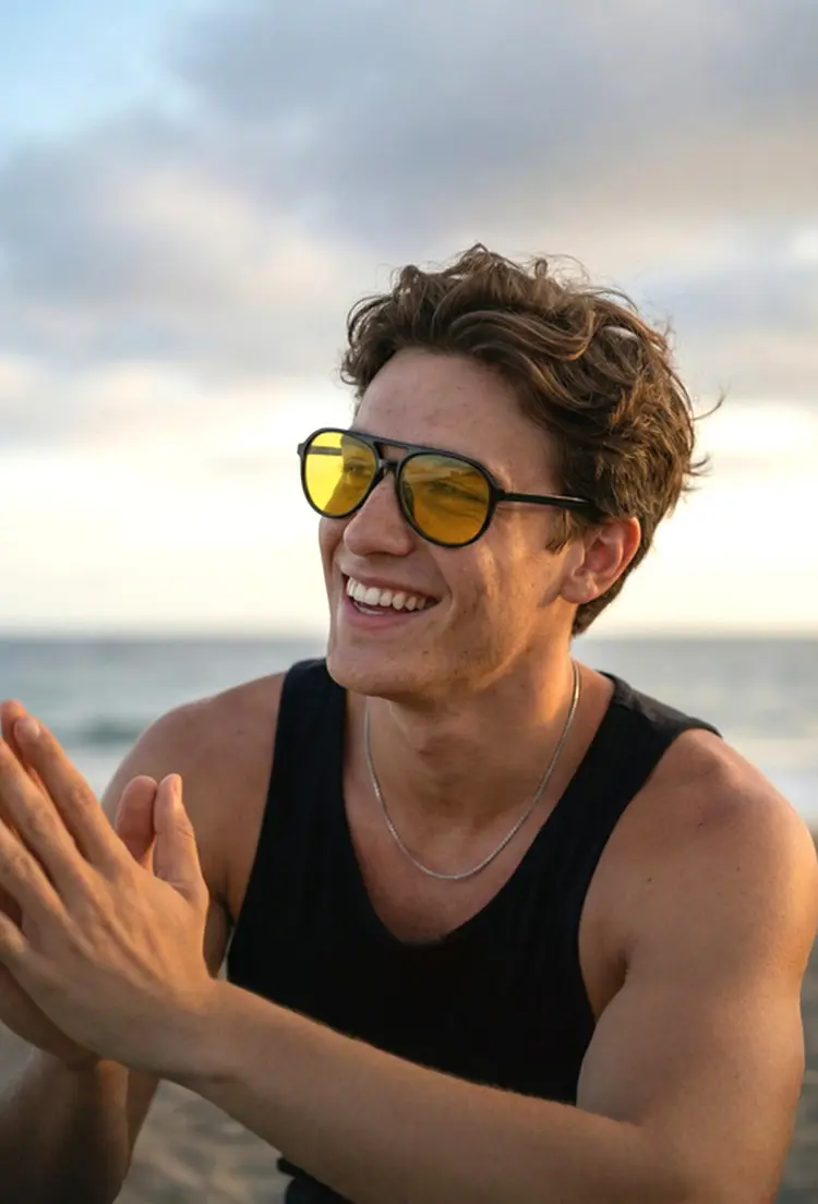 Male model wearing magnetic black aviator tr90 magnetic clip-on eyeglasses set with interchangeable clip-on lenses smiling in a black tank top on a sunset beach. SPU: AR0122601