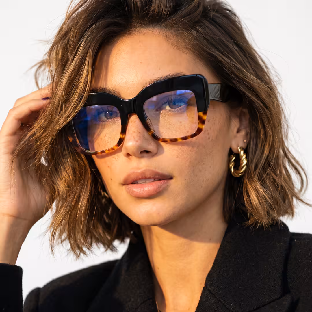 Front view of female wearing tortoise cat eye eyeglasses, hand in hair, natural smile, CA0032503