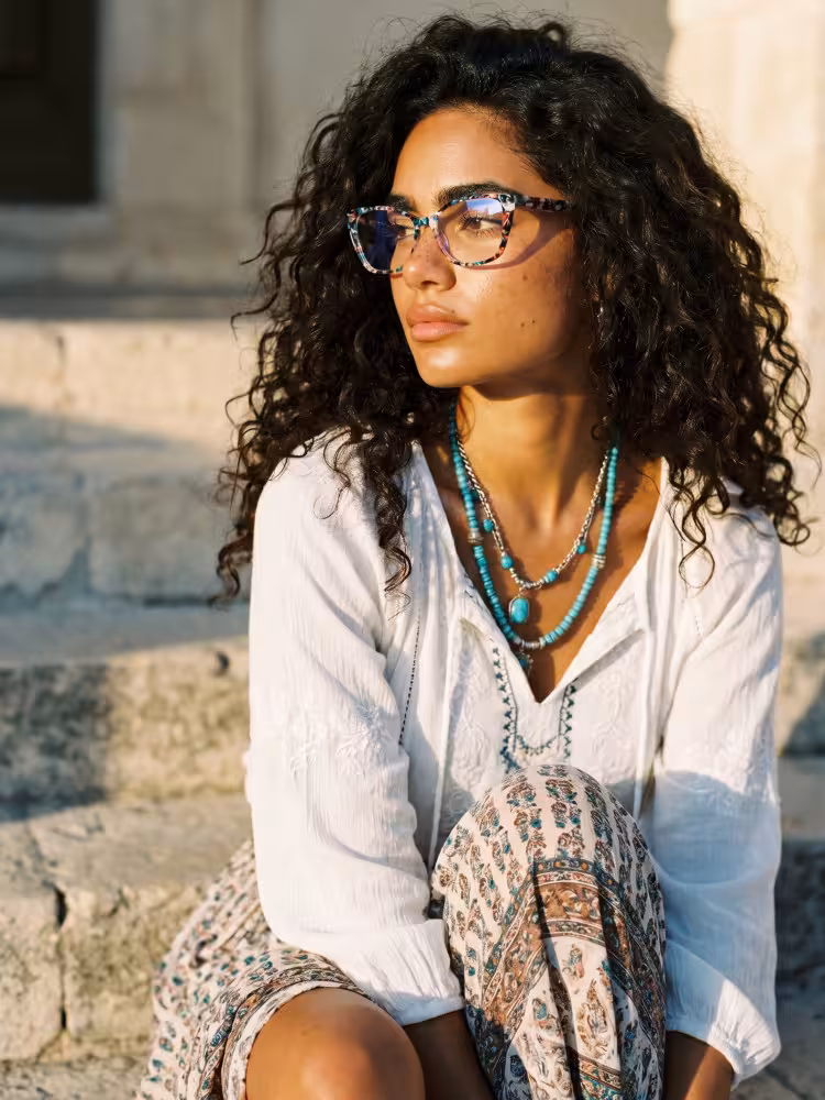 Female model wearing colorful tortoise cat eye acetate eyeglasses in a sunlit stone outdoor setting. SPU: CA0092307