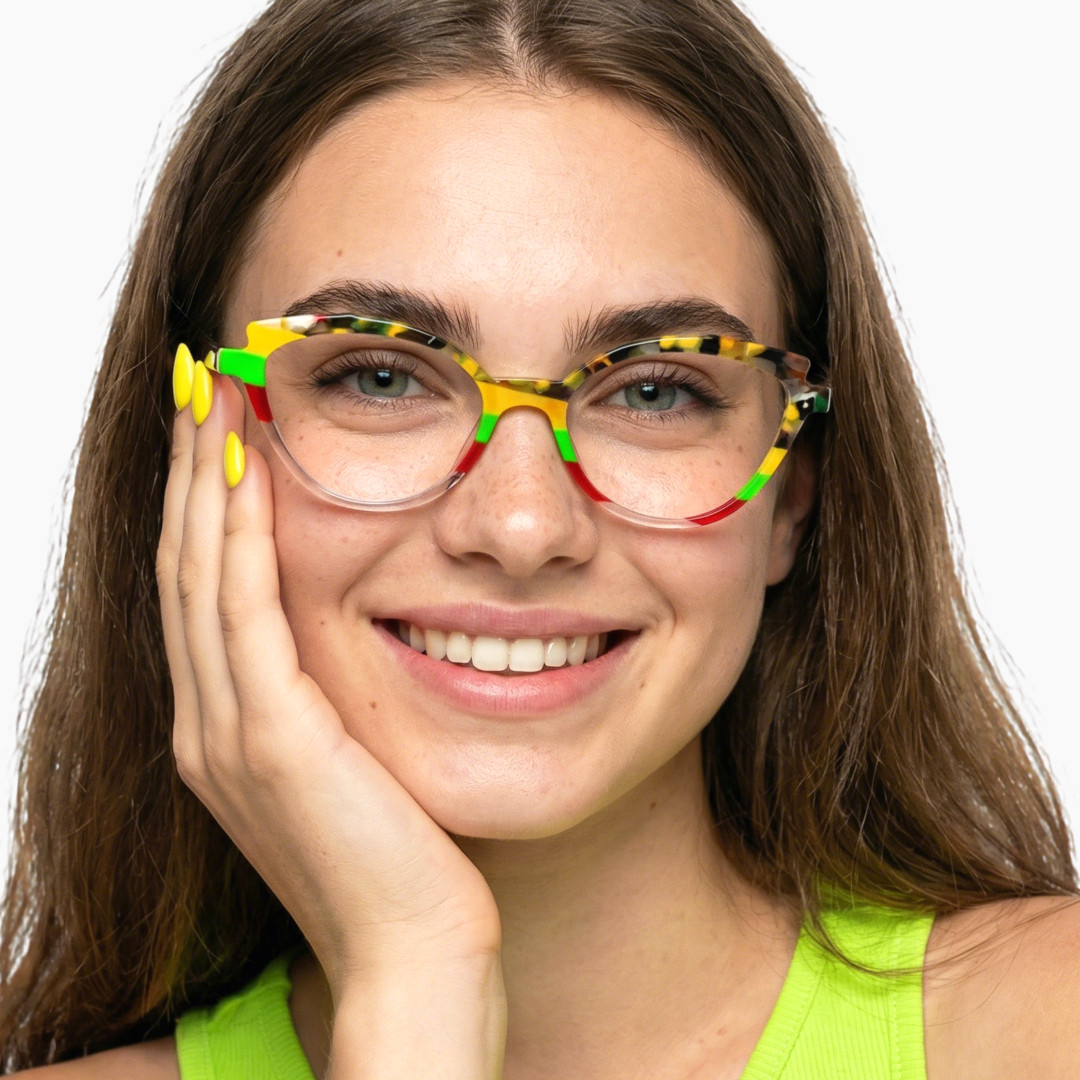 Front view of female wearing colorful multicolor cat eye eyeglasses, hand near face, smiling, CA0222306