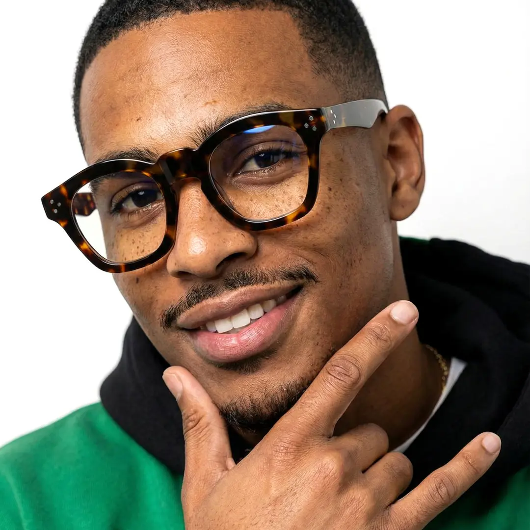 Looking straight ahead view of male wearing tortoise cat eye eyeglasses, hand touching chin, smiling, CA0542302