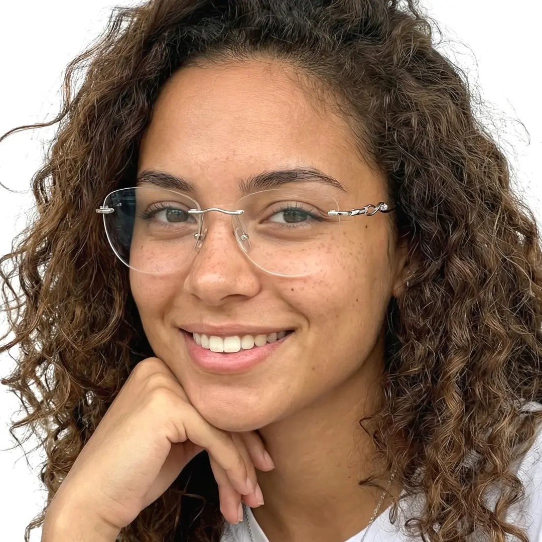 Three-quarter view of female wearing silver cat eye eyeglasses, resting chin on hand, natural smile, CM0032603