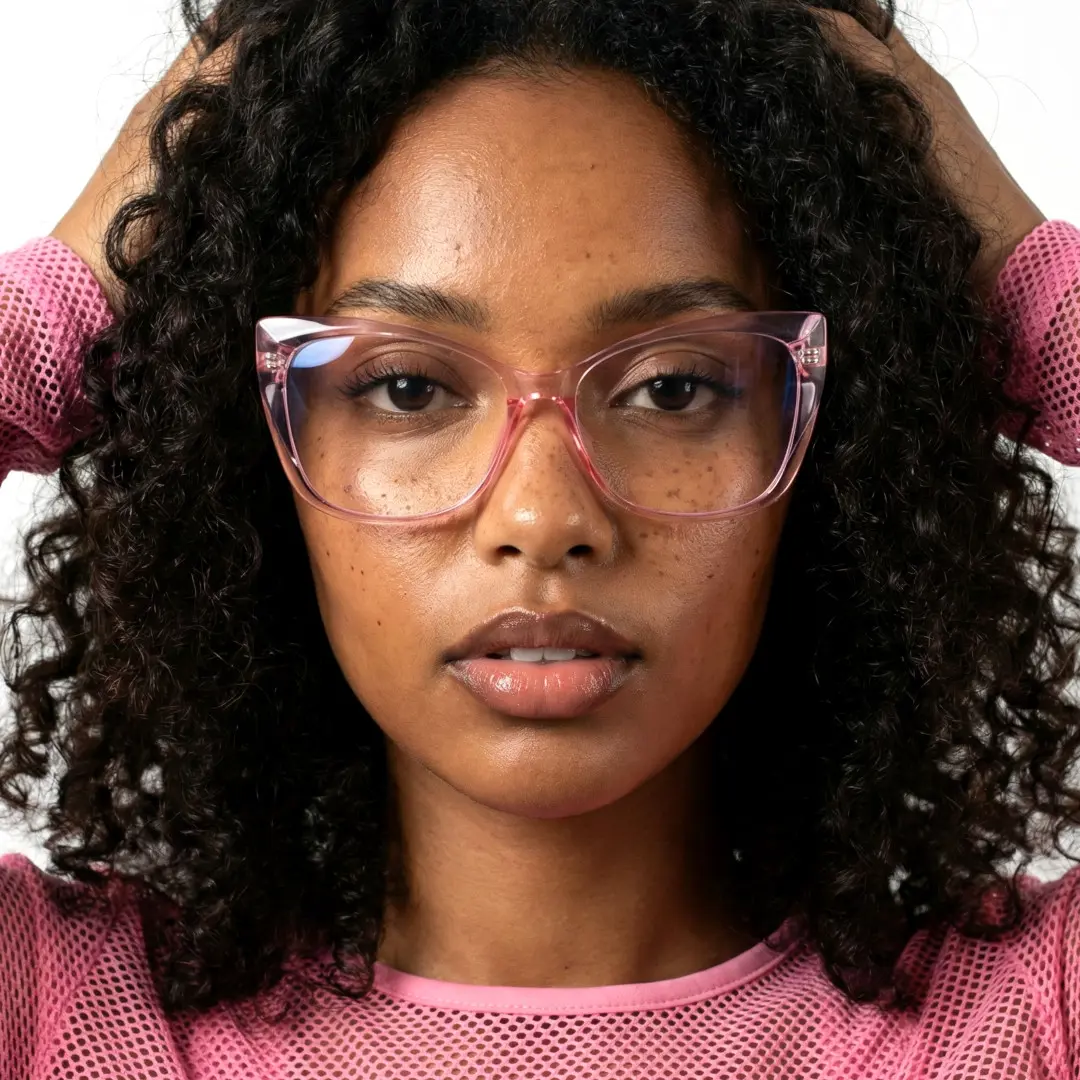 Close-up view of female wearing pink cat eye eyeglasses, hand in hair, neutral expression, CP0062209