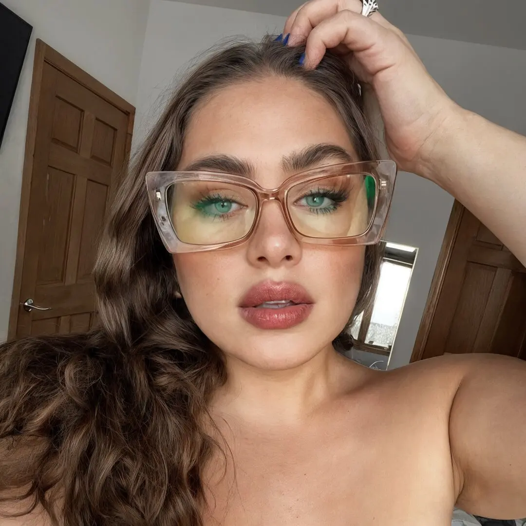 Front view of female wearing brown butterfly eyeglasses, hand in hair, neutral expression, CP0162310