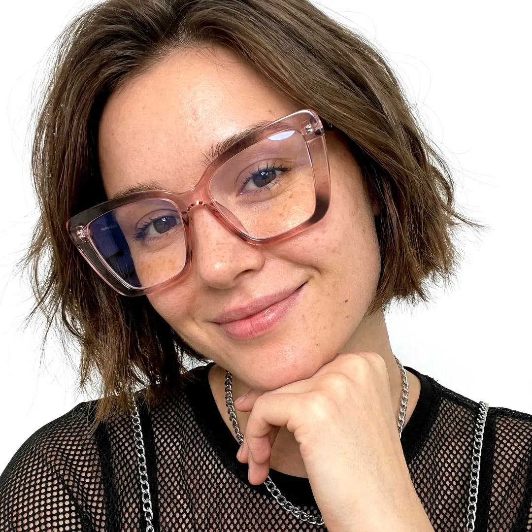 Front view of female wearing pink cat eye eyeglasses, resting chin on hand, friendly smile, CP0342506