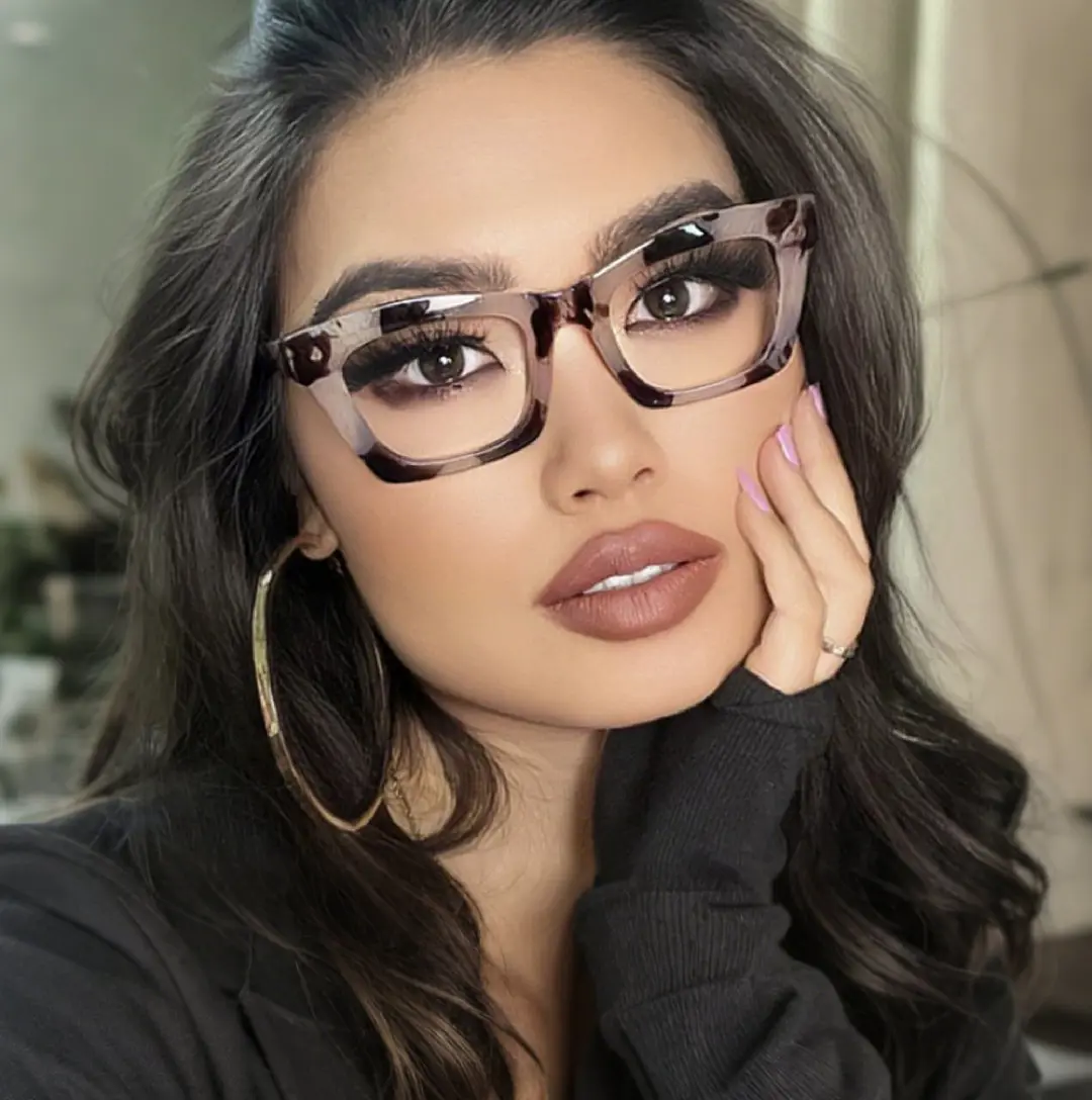 Face close-up view of female wearing tortoise cat eye eyeglasses, hand near face, neutral expression, CR0012209