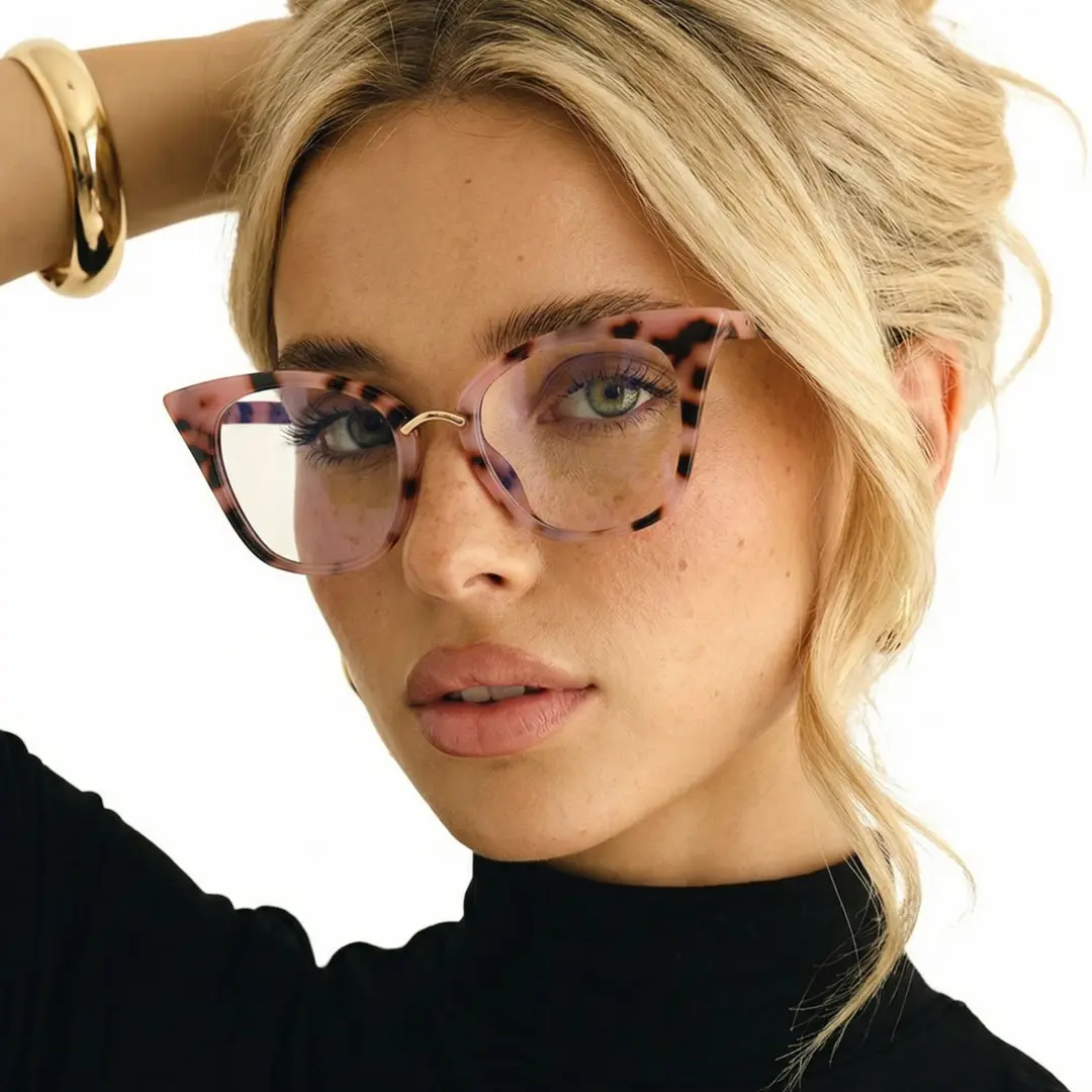 Profile view of female wearing red tortoise cat eye eyeglasses, hand in hair, neutral expression, CR0012211