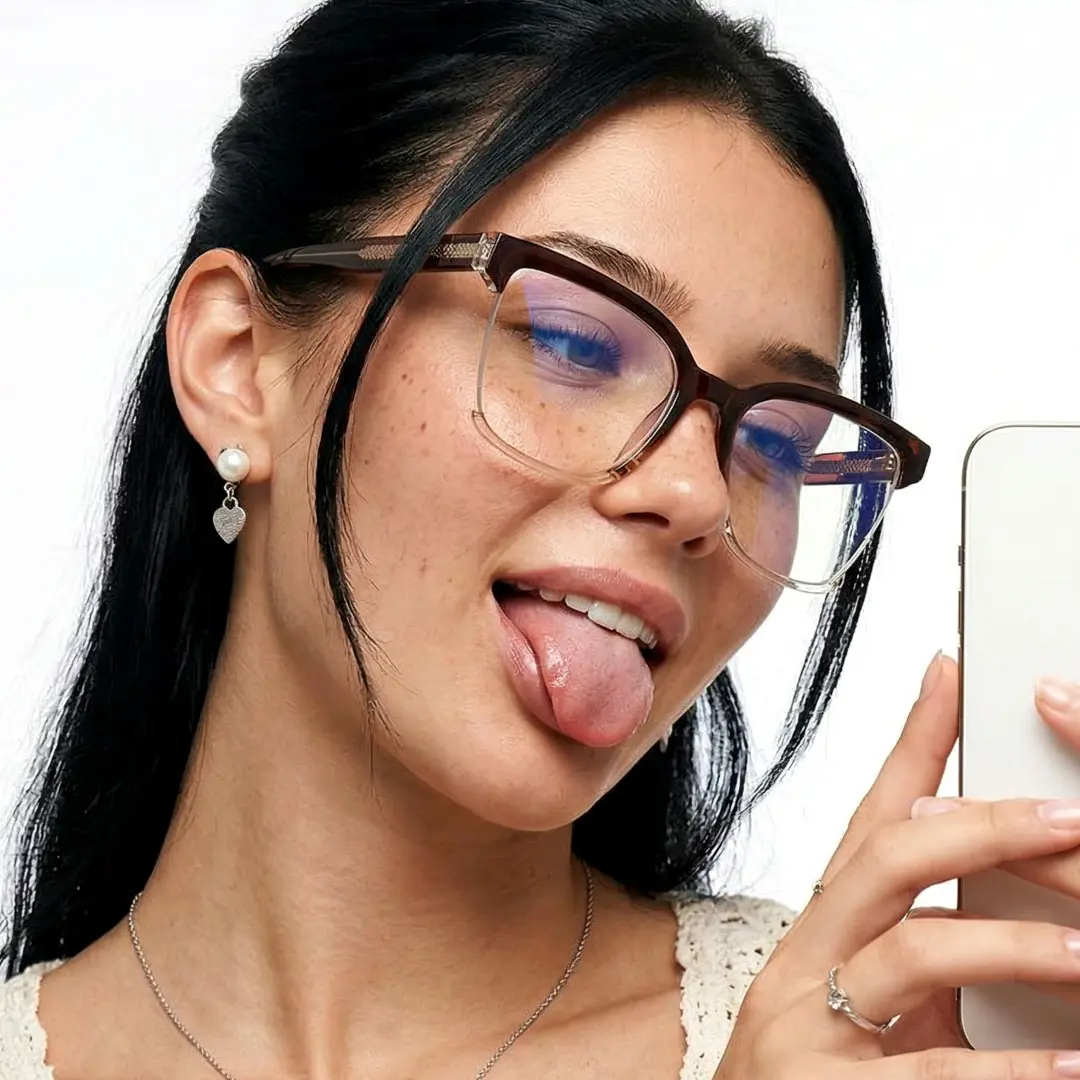 Three-quarter view of female wearing brown cat eye eyeglasses, playful expression, taking a selfie, CR0022502