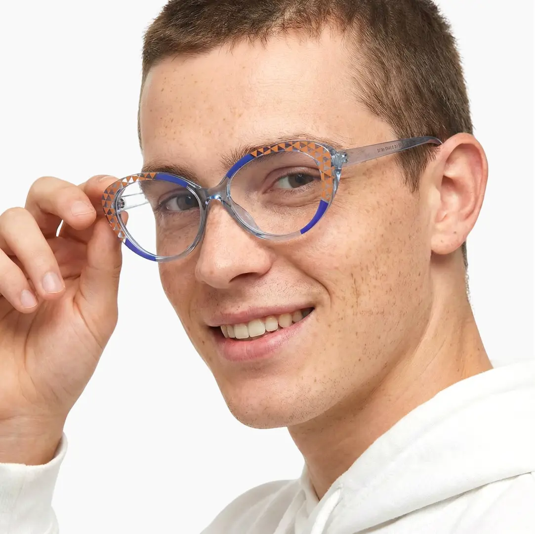 Over-the-shoulder view of male wearing blue cat eye eyeglasses, holding glasses, smiling, CR0042405