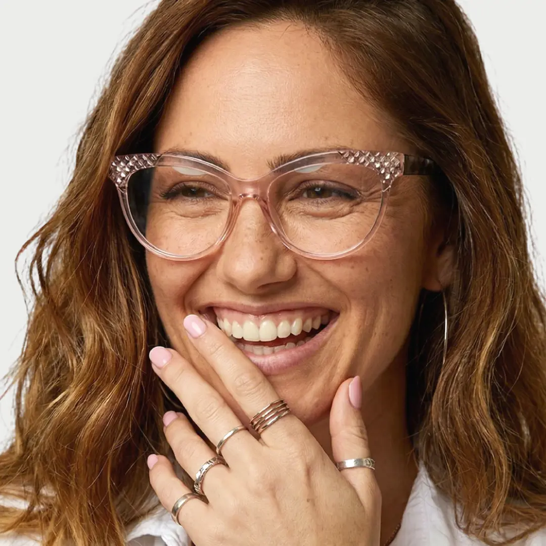 Slightly angled view of female wearing light pink cat eye eyeglasses, smiling, CR0052303