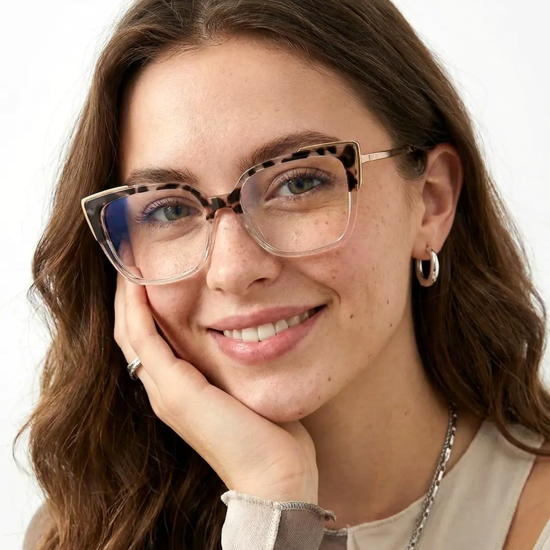 Three-quarter view of female wearing brown tortoise cat eye eyeglasses, resting chin on hand, smiling, CR0052409