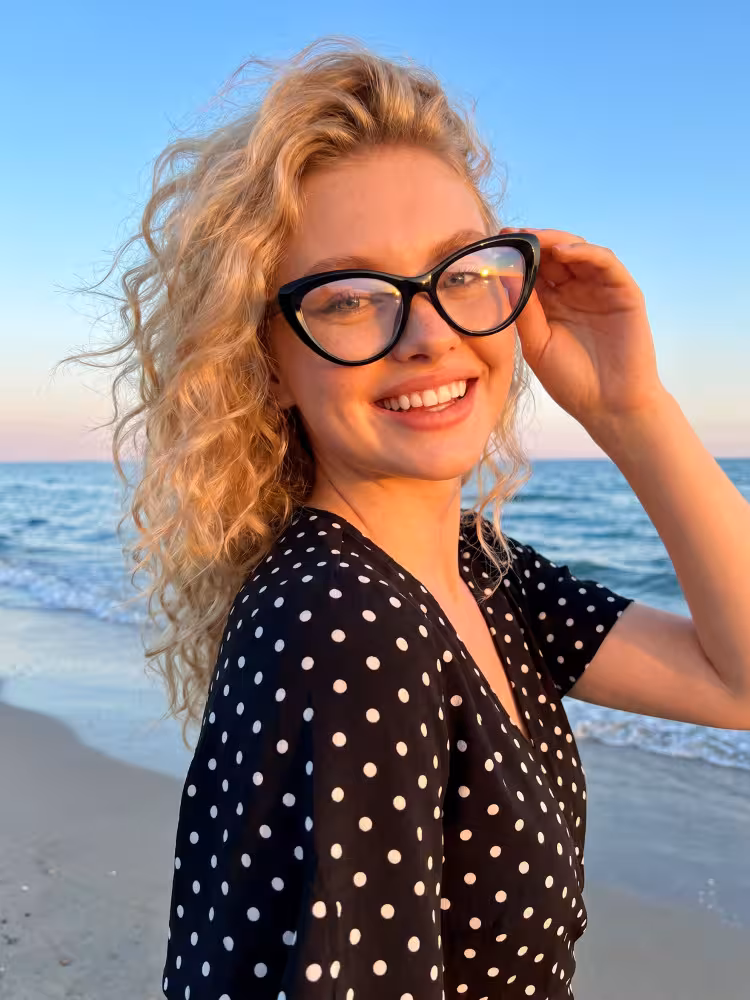 Female model wearing vintage black cat eye tr90 eyeglasses at seaside beach during sunset. SPU:CR0072404