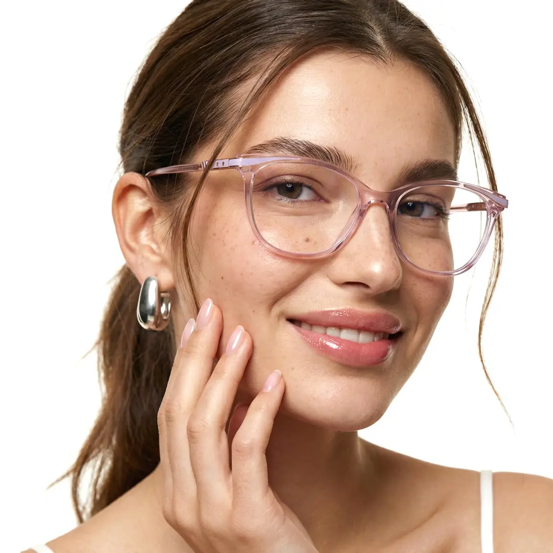 Three-quarter view of female wearing pink cat eye eyeglasses, resting chin on hand, natural smile, CR0072408