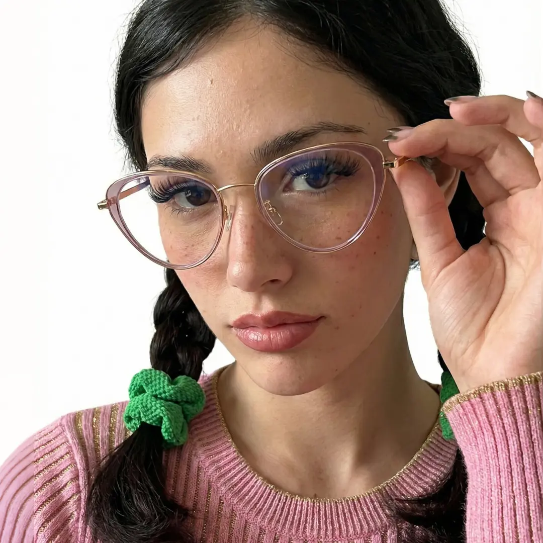 Three-quarter view of female wearing purple cat eye eyeglasses, holding glasses, neutral expression, CR0072411