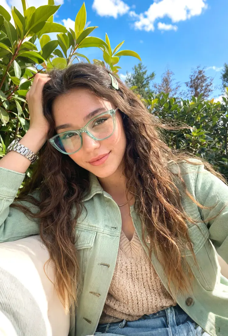 Female model wearing everyday green cat eye tr90 eyeglasses in a sunny outdoor garden. SPU: CR0072603