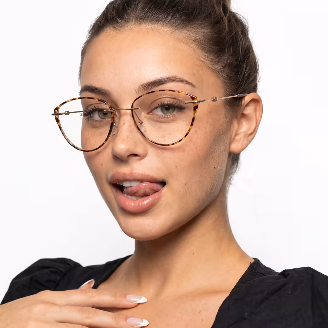 Front view of female wearing vintage tortoise cat eye eyeglasses, sticking out tongue, friendly smile, CR0072604