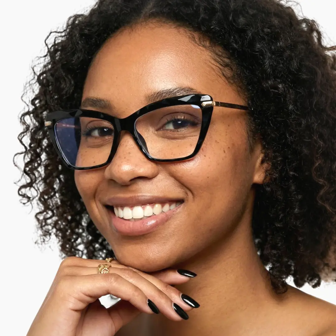 Three-quarter view of female wearing black cat eye eyeglasses, resting chin on hand, smiling, CR0082502