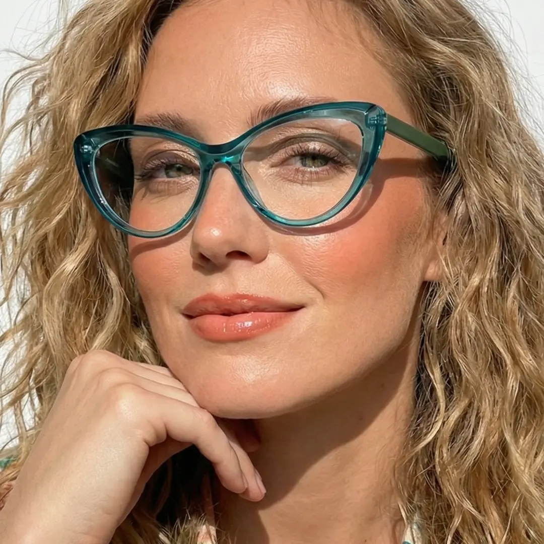 Front view of female wearing green cat eye eyeglasses, resting chin on hand, soft smile, CR0102502
