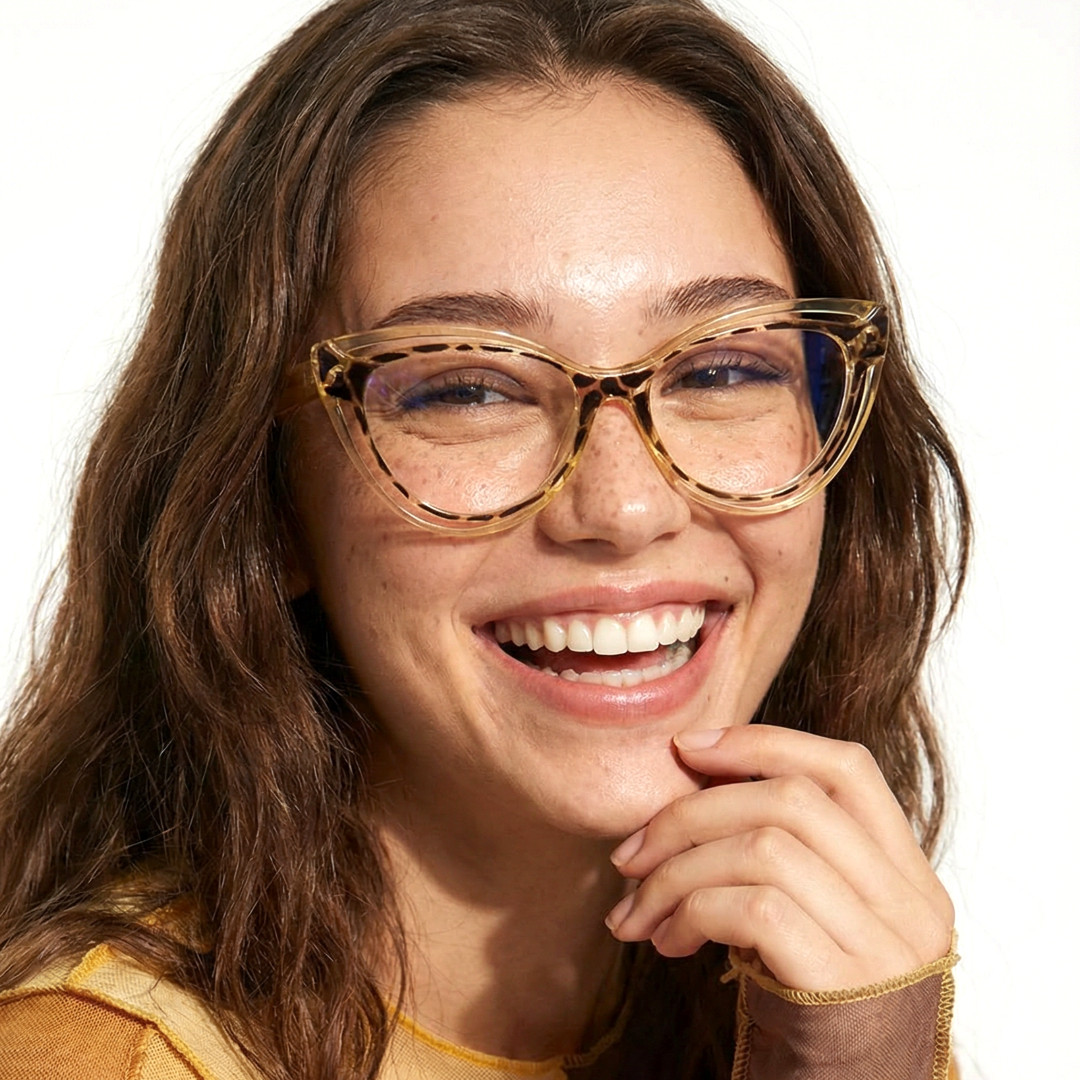 Front view of female wearing vintage yellow cat eye eyeglasses, resting chin on hand, smiling, CR0132408