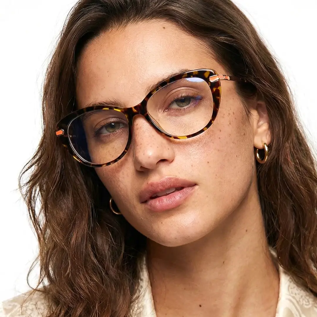 Front view of female wearing tortoise cat eye eyeglasses, tilting head, neutral expression, CR0162502