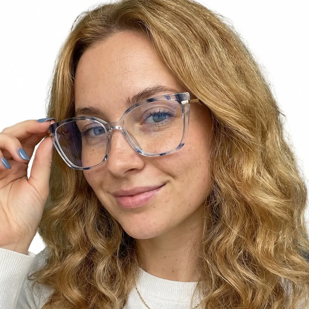 Three-quarter view of female wearing blue cat eye eyeglasses, touching frame, smiling, CR0252408