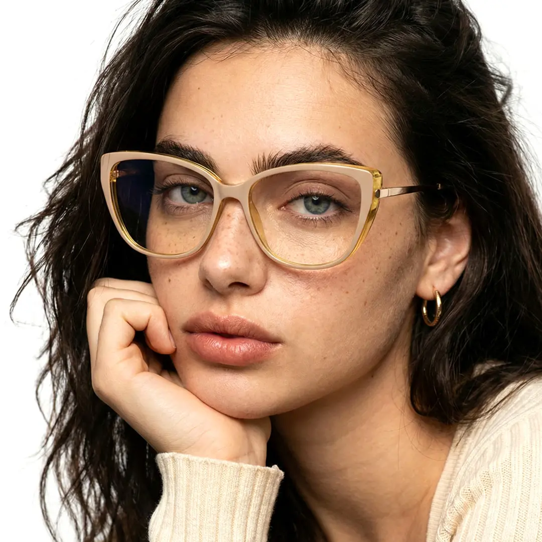 Three-quarter view of female wearing beige cat eye eyeglasses, resting chin on hand, neutral expression, CR0262310