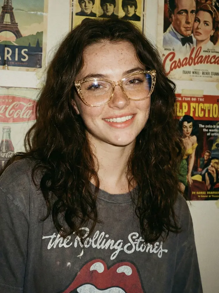 Female model wearing glitter yellow cat eye tr90 eyeglasses in front of a wall covered with vintage posters. SPU: CR0372504