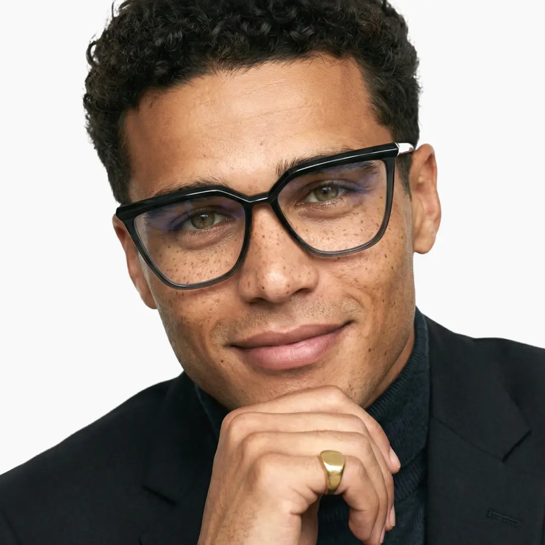 Front view of male wearing black cat eye eyeglasses, resting chin on hand, natural smile, CR0442302