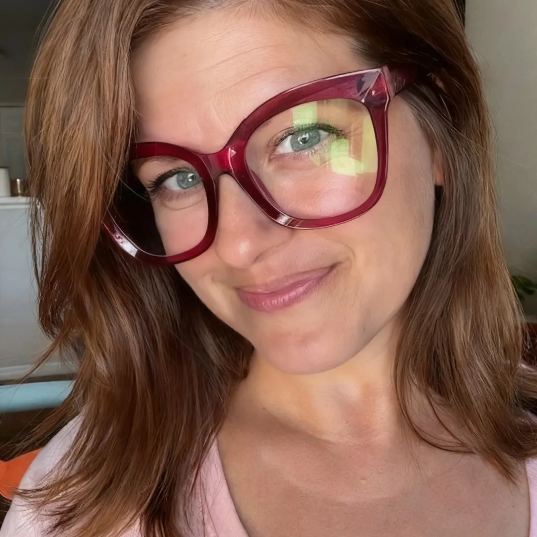 Face close-up view of female wearing pink cat eye eyeglasses, friendly smile, CR0532505