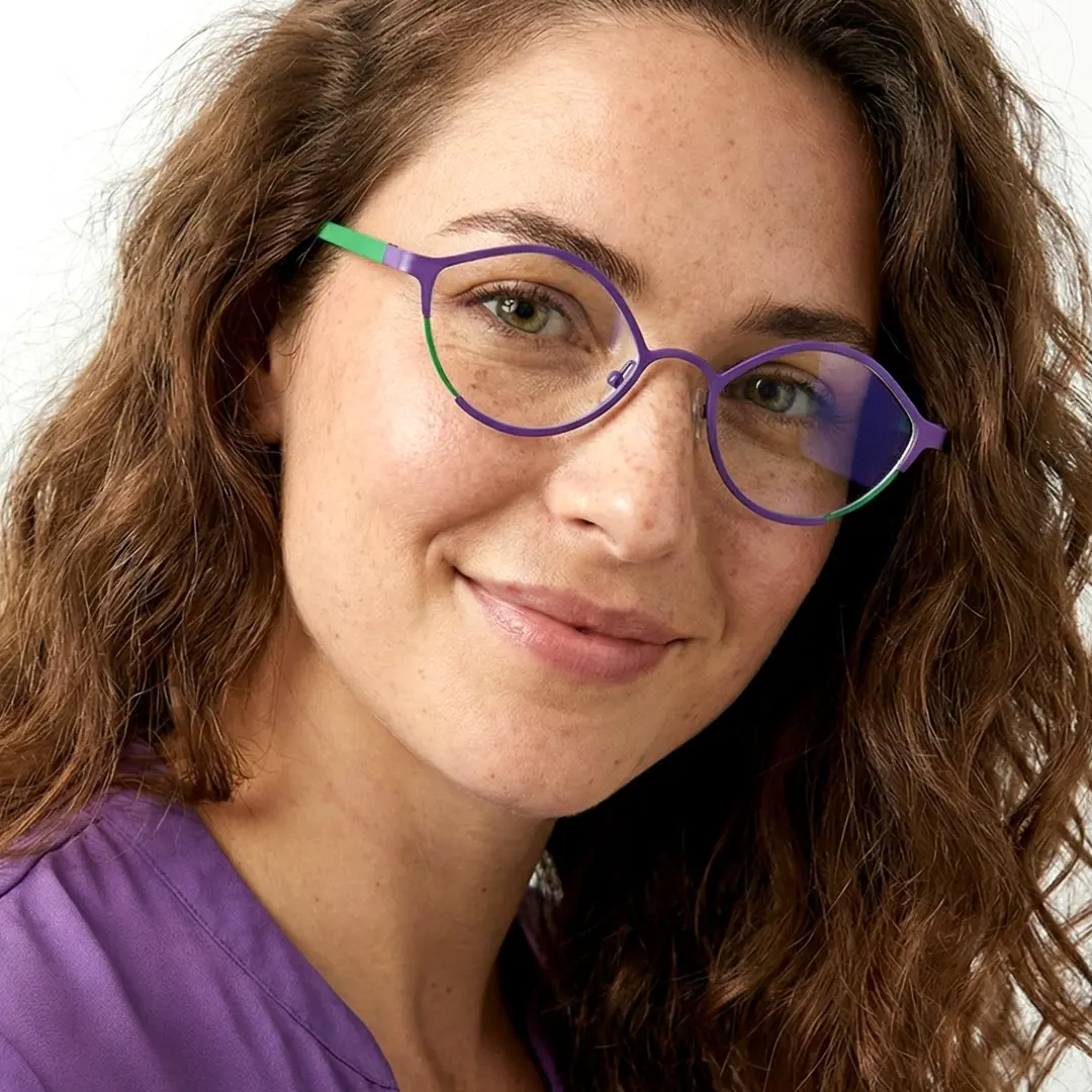 Face close-up of female wearing purple cat eye eyeglasses, looking straight ahead, friendly smile, CT0062407