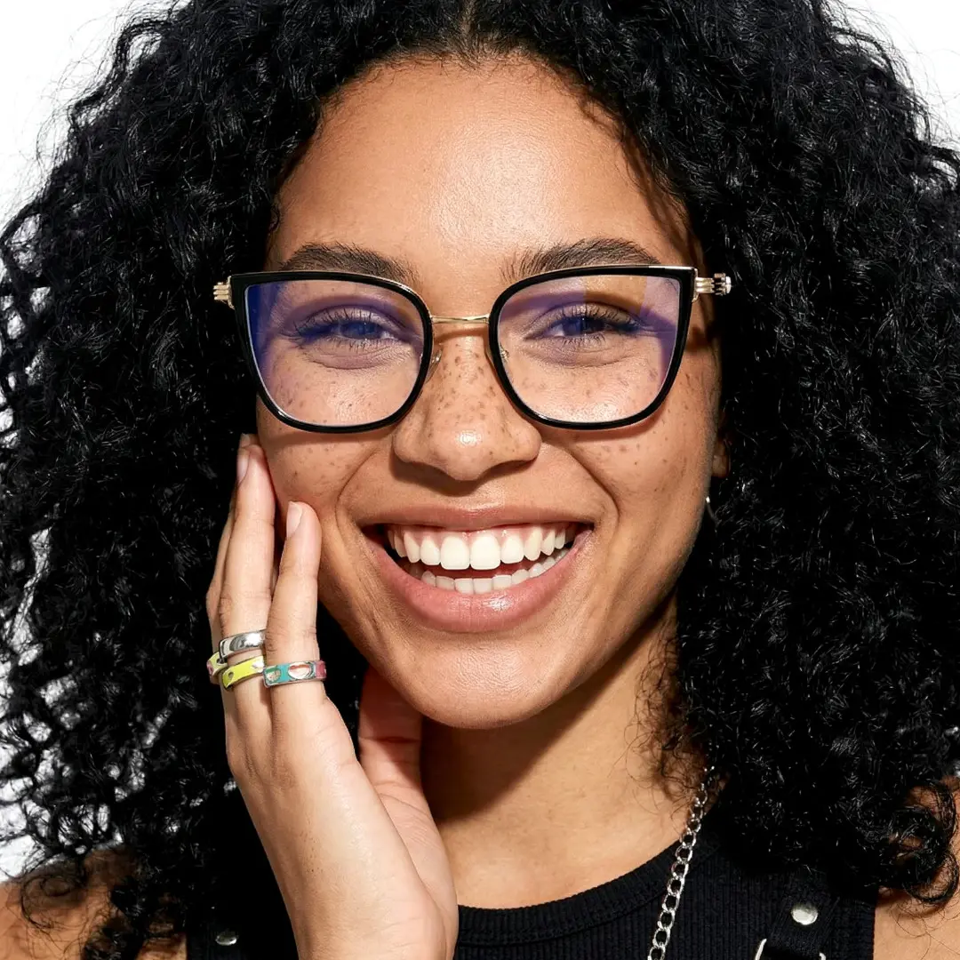 Front view of female wearing black cat eye eyeglasses, hand touching face, smiling, CX0052604