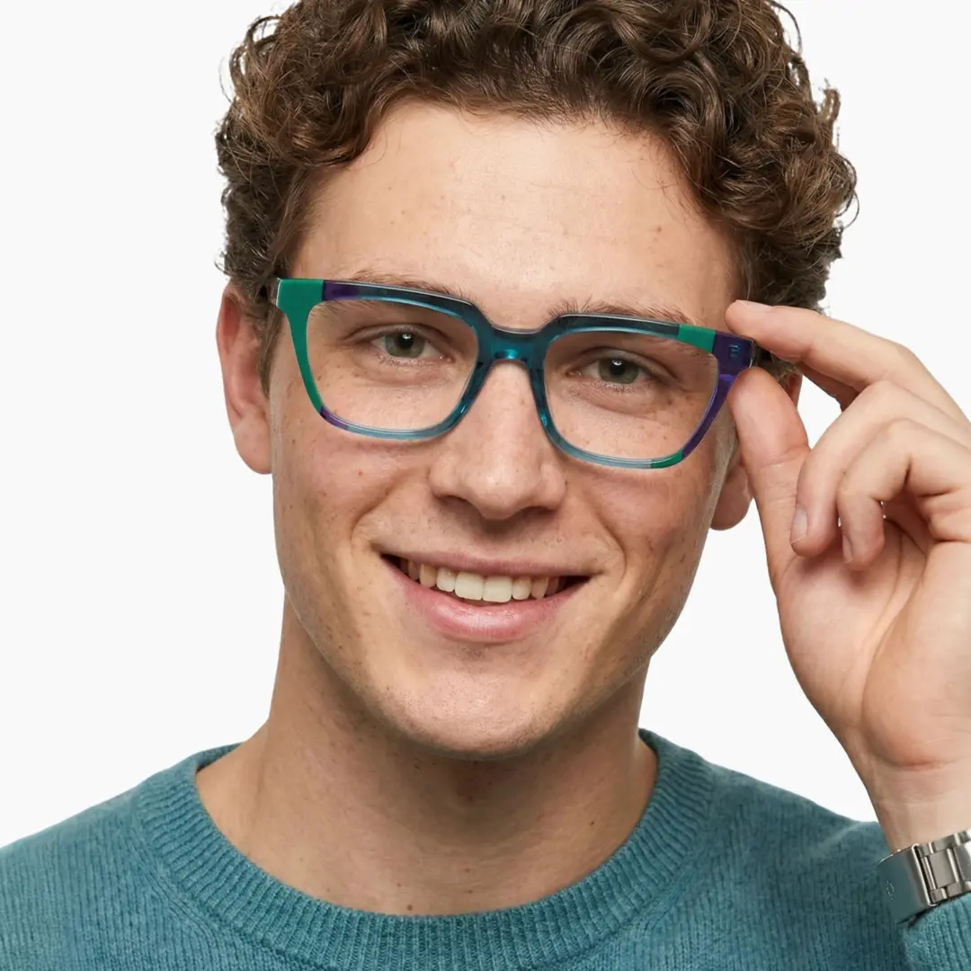 Front view of male wearing colorful green rectangle eyeglasses, holding glasses, smiling, EA0042209