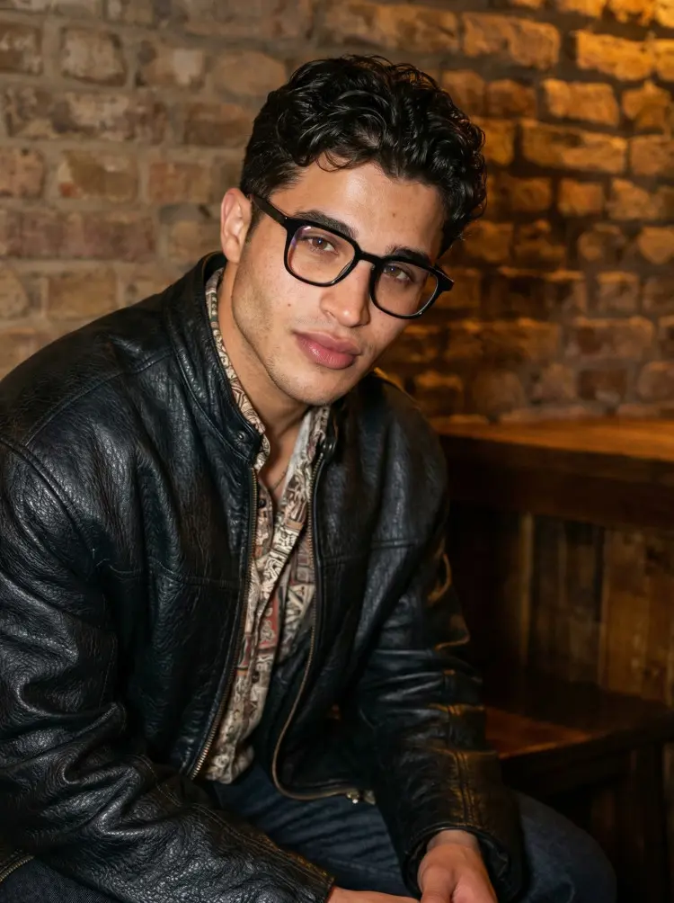 Male model wearing vintage black rectangle acetate eyeglasses in a cozy bar with a vintage brick wall background. SPU: EA0122509