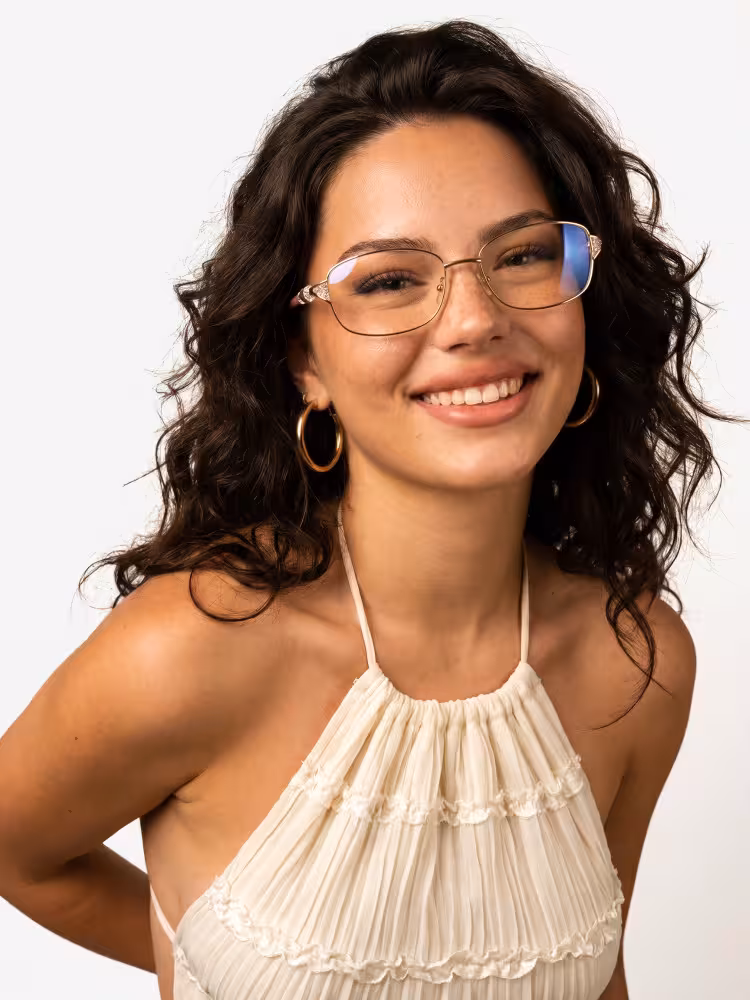 Female model wearing luxury gold rectangle metal eyeglasses in an indoor photo studio with plain solid off-white seamless background. SPU: EM0212605
