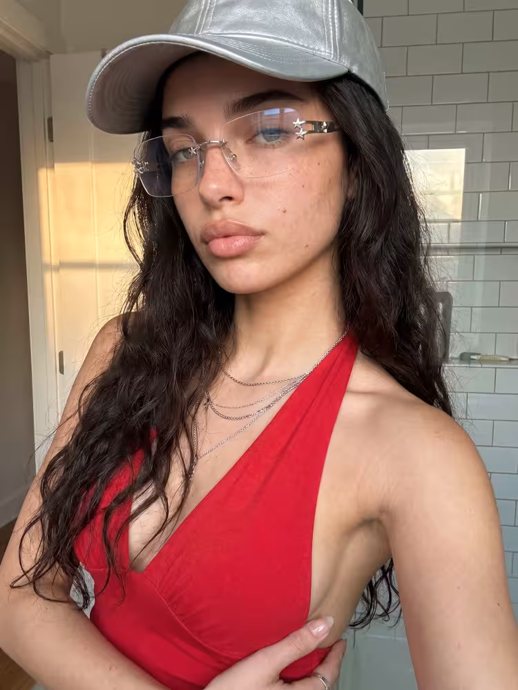 Female model wearing rimless silver rectangle metal handcrafted polarized eyeglasses against a minimalist light grey wall background. SPU: EM0302512