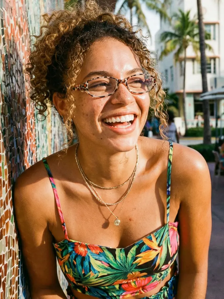 Female model wearing everyday multicolor rectangle pc eyeglasses in a floral tropical strap top laughing next to a mosaic tile wall with a palm tree background. SPU: EP0342601