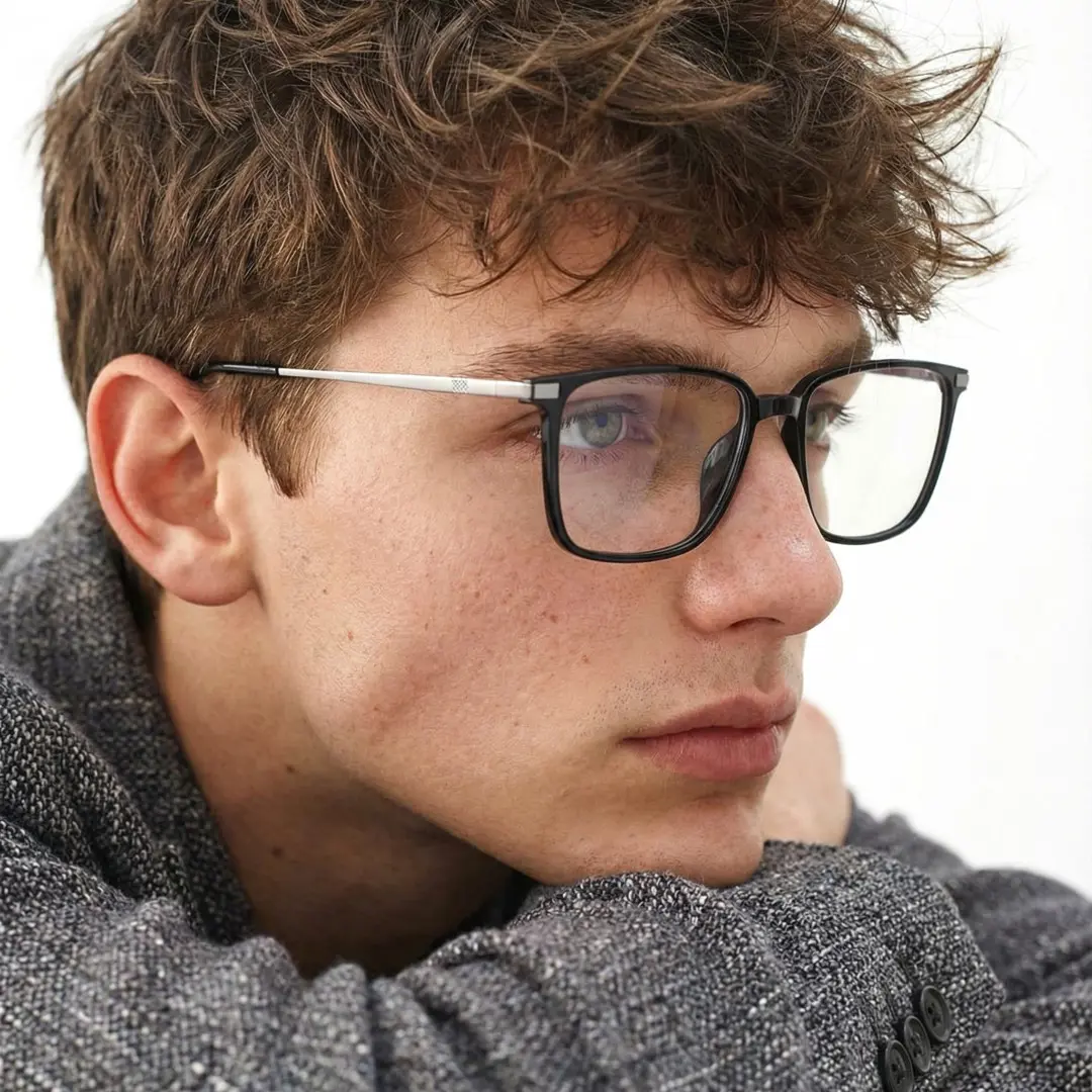 Looking away view of male wearing black rectangle eyeglasses, resting chin on hand, confident expression, ER0172508