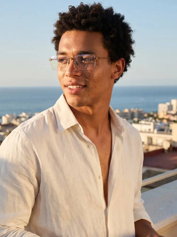 Male model wearing luxury silver rectangle titanium eyeglasses on a rooftop overlooking the ocean. SPU: ET0042604