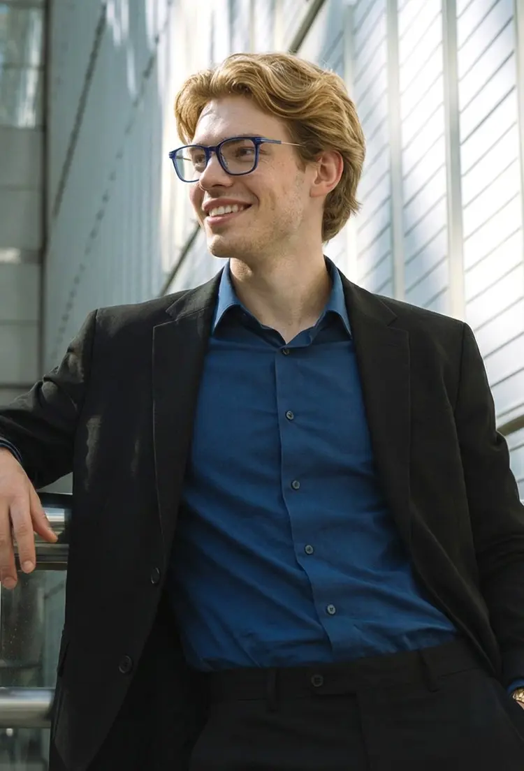 Male model wearing vintage blue rectangle titanium eyeglasses standing in front of a modern building with glass windows. SPU: ET0312208